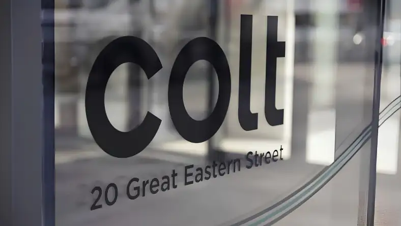Glass entrance panel with the Colt company name and 20 Great Eastern Street address, street visible behind