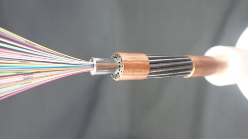 Close-up of a subsea optical cable cross-section revealing coloured fibers emerging from a copper connector