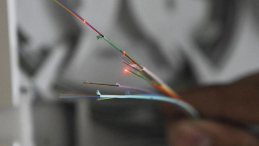 Close-up of multicolour fibre optic cables with red light transmission points against a blurred background